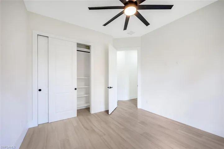 Unfurnished bedroom featuring light wood-style flooring, a closet, a ceiling fan, visible vents, and baseboards