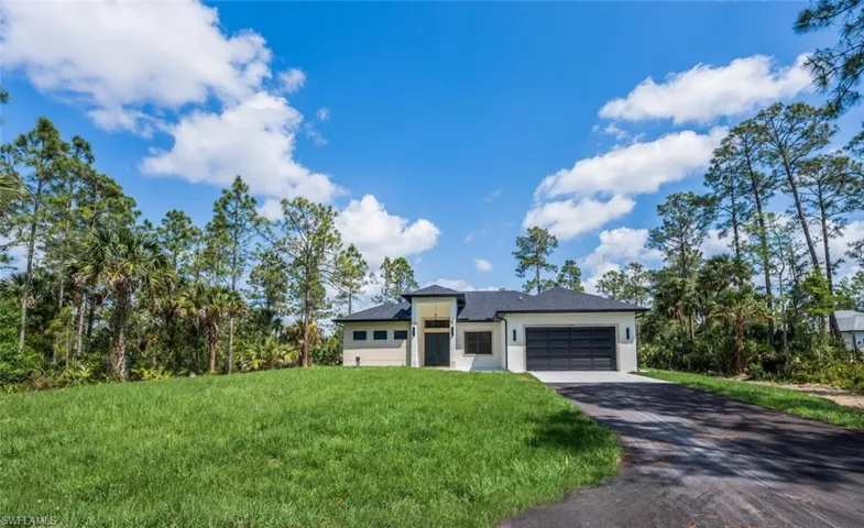 Prairie-style house with aphalt driveway, stucco siding, an attached garage, and a front yard