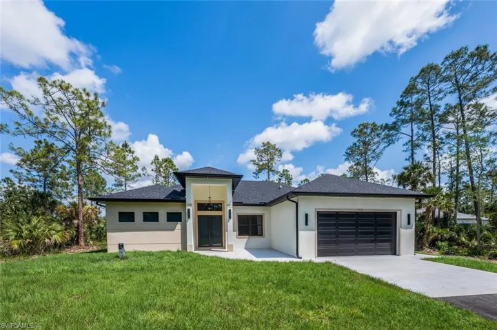 Prairie-style house with a front yard, a shingled roof, a garage, concrete driveway, and stucco siding