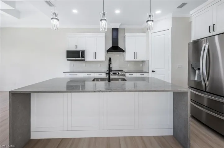 Kitchen with decorative backsplash, wall chimney exhaust hood, visible vents, and stainless steel appliances