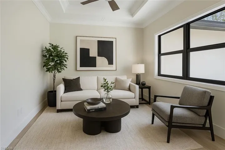 Living area featuring a ceiling fan, baseboards, light wood-style floors, and a raised ceiling