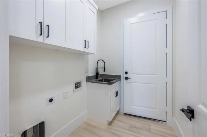 Laundry area featuring washer hookup, a sink, light wood-style floors, hookup for an electric dryer, and cabinet space