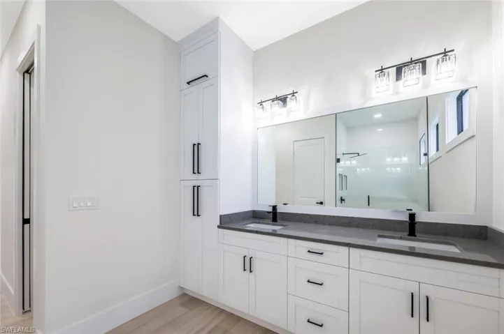 Bathroom featuring a sink, baseboards, a stall shower, and wood finished floors