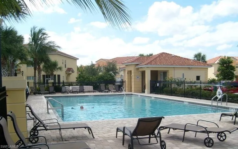 Outdoor swimming pool with integrated steps and handrails, surrounded by a paver deck