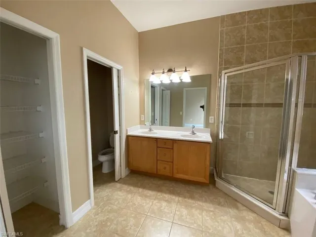 Bathroom featuring a dual vanity with a light wood-finish cabinet, white countertops, and a large mirror