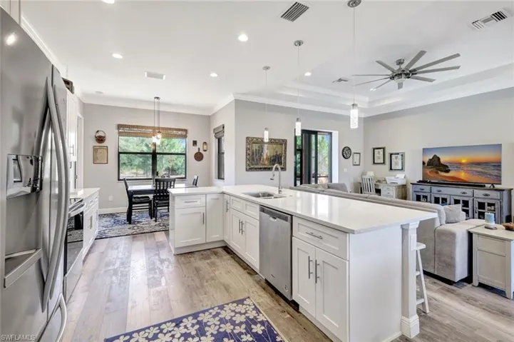 Kitchen with stainless steel appliances, open floor plan, a sink, light wood finished floors, and ornamental molding