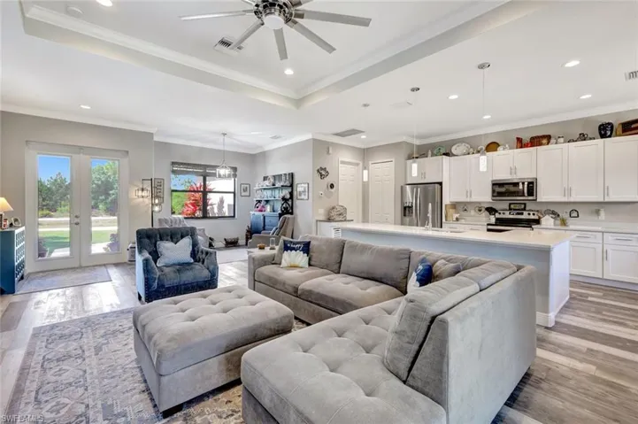 Living room with a tray ceiling, recessed lighting, ceiling fan, light wood-style flooring, and french doors