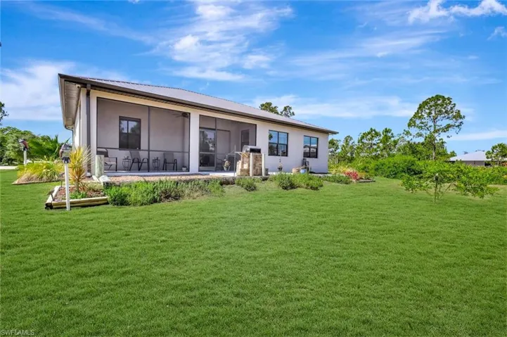 Rear view of property with stucco siding, a yard, a sunroom, and ceiling fan