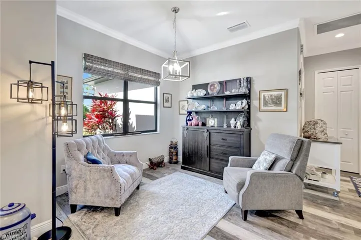 Living area featuring wood finished floors, ornamental molding, a chandelier, baseboards, and recessed lighting