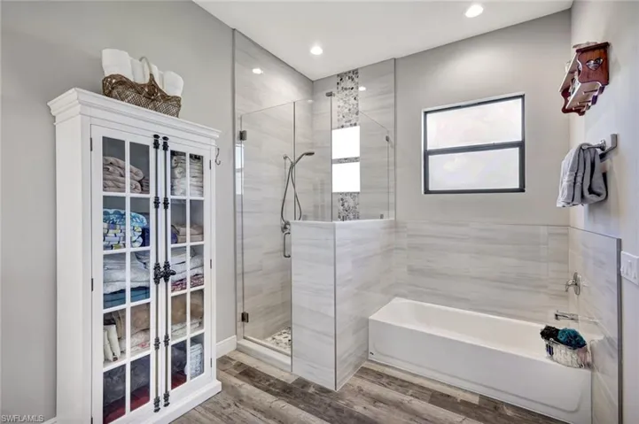 Bathroom with a stall shower, a bath, recessed lighting, and wood finished floors