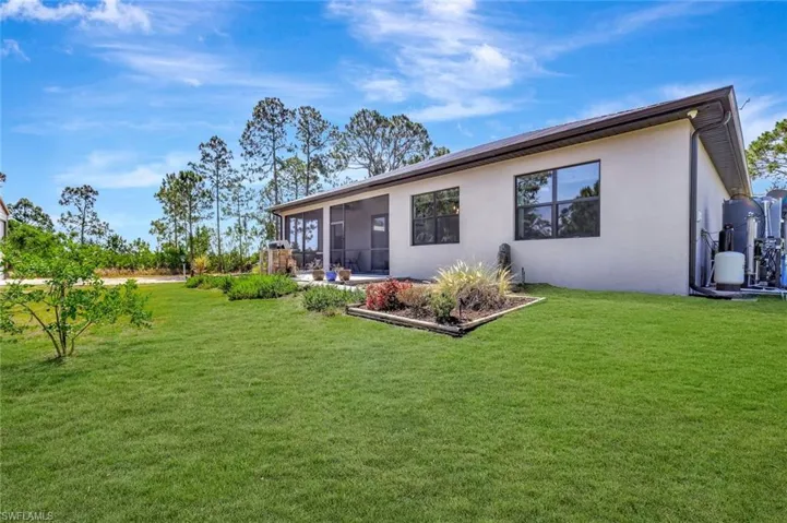 Rear view of house featuring stucco siding, a sunroom, and a lawn