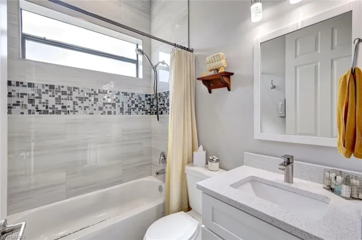 Full bathroom with shower / bathtub combination with curtain, toilet, and vanity