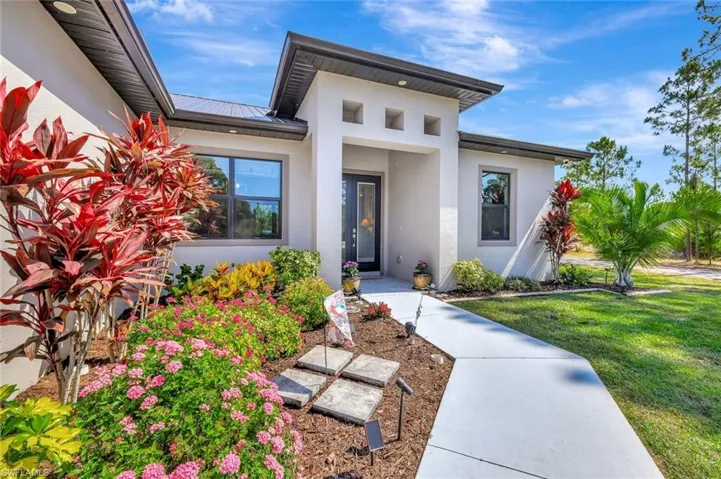 Doorway to property with stucco siding, a lawn, and metal roof