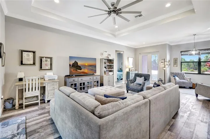 Living area with a tray ceiling, wood finished floors, ceiling fan, recessed lighting, and crown molding