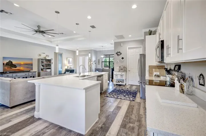 Kitchen featuring appliances with stainless steel finishes, crown molding, open floor plan, a sink, and a ceiling fan