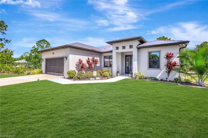 Prairie-style house featuring stucco siding, driveway, a front lawn, and a garage