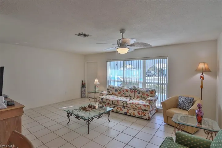 Living room featuring light tile patterned flooring, ceiling fan, and a textured ceiling