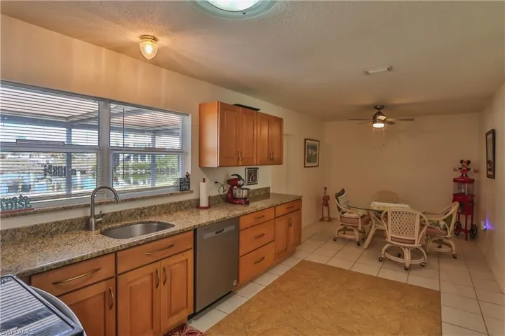 Kitchen with light tile patterned floors, sink, ceiling fan, range, and stainless steel dishwasher