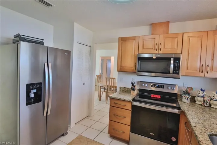 Kitchen with light stone counters, light tile patterned floors, light brown cabinets, and appliances with stainless steel finishes