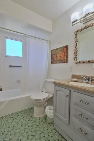 Full bathroom with shower / bath combination with curtain, tile patterned floors, vanity, and toilet
