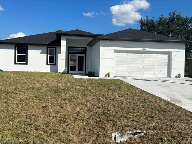 View of front facade featuring a front yard and a garage