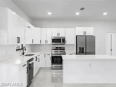 Kitchen with sink, appliances with stainless steel finishes, and white cabinetry