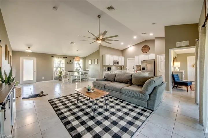 Living area with light tile patterned floors, a ceiling fan, and high vaulted ceiling