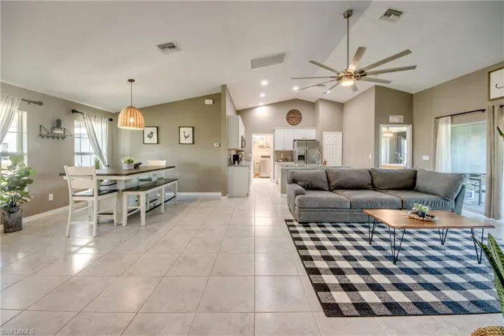 Living area with ceiling fan, light tile patterned floors, and lofted ceiling
