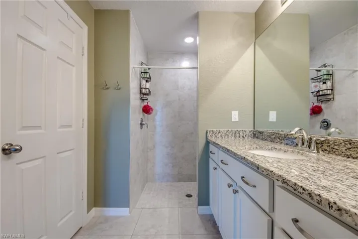 Full bathroom with vanity, tiled shower, and tile patterned flooring