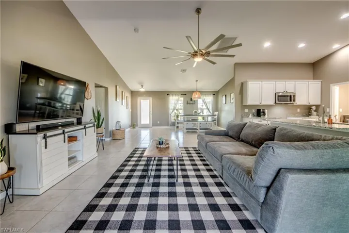Living room featuring light tile patterned flooring, a ceiling fan, high vaulted ceiling, and recessed lighting