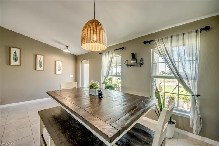 Dining room featuring healthy amount of natural light, light tile patterned floors, and vaulted ceiling