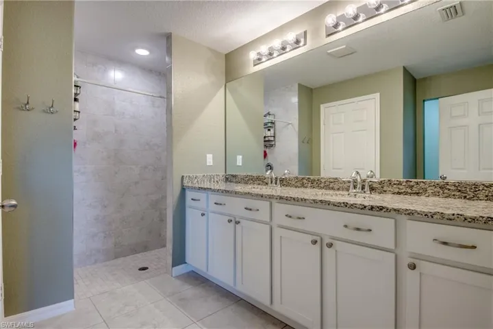 Full bath featuring walk in shower, double vanity, and tile patterned floors