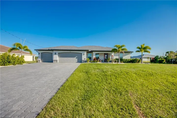 Single story home with a garage, a front lawn, decorative driveway, and stucco siding