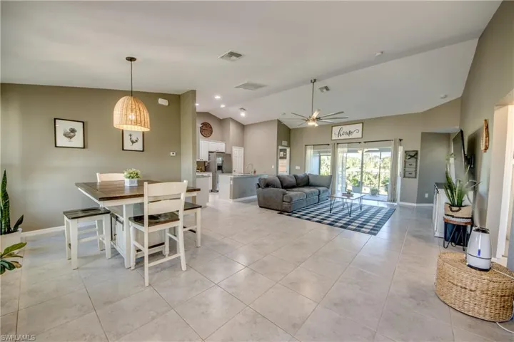 Dining area featuring vaulted ceiling, a ceiling fan, and light tile patterned flooring