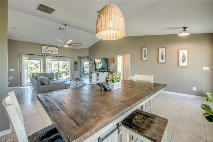 Dining area featuring ceiling fan, light tile patterned flooring, and high vaulted ceiling