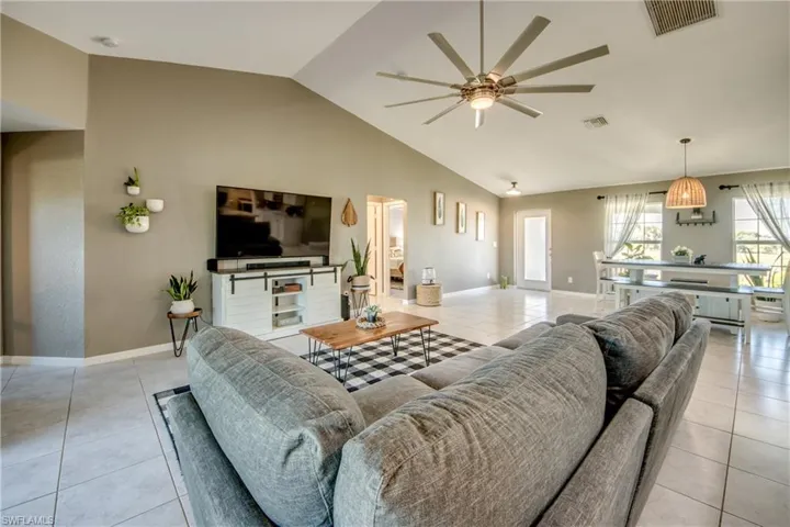 Living room with light tile patterned flooring, ceiling fan, and high vaulted ceiling
