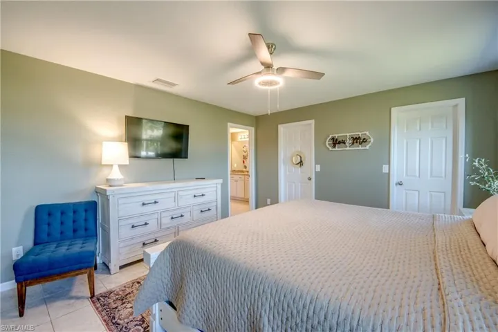 Bedroom with light tile patterned flooring, a ceiling fan, and connected bathroom