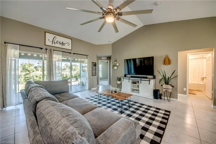 Living area featuring light tile patterned floors, a ceiling fan, and high vaulted ceiling