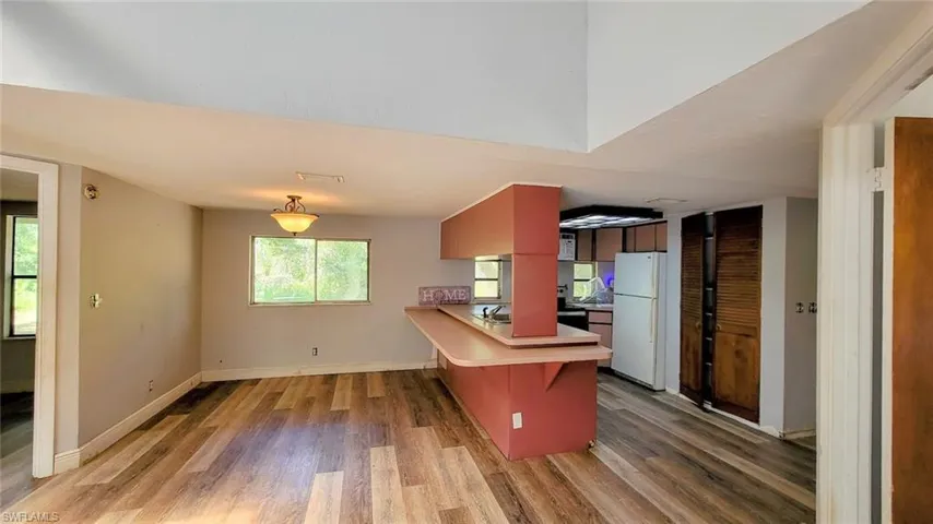 Kitchen featuring white refrigerator, hardwood / wood-style flooring, a breakfast bar area, and a wealth of natural light