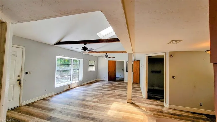 Living room featuring ceiling fan, light hardwood / wood-style floors, and lofted ceiling with skylight