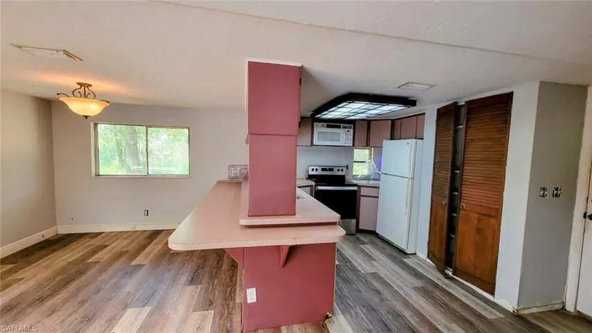 Kitchen featuring light hardwood / wood-style floors, white appliances, and a breakfast bar