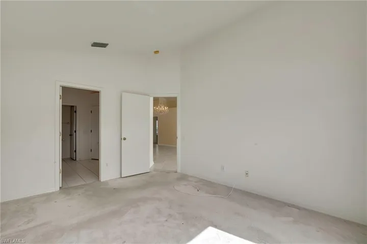 Spare room featuring lofted ceiling and an inviting chandelier