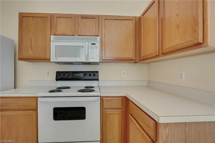 Kitchen featuring light brown cabinetry and white appliances