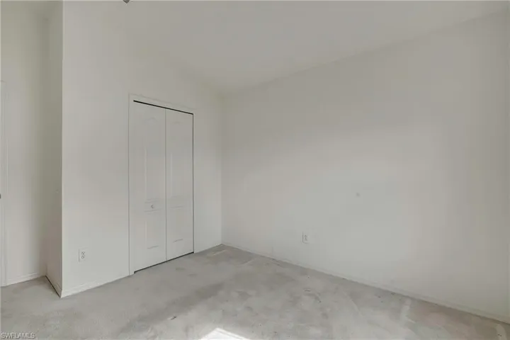 Unfurnished bedroom with light colored carpet, lofted ceiling, and a closet