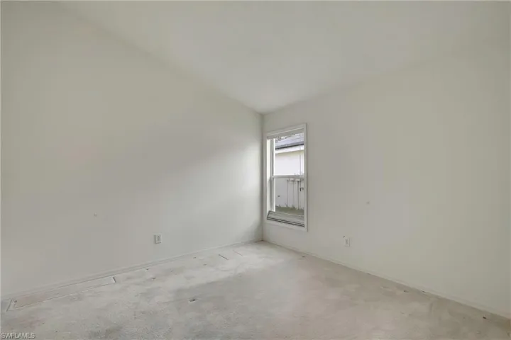 Carpeted empty room featuring lofted ceiling