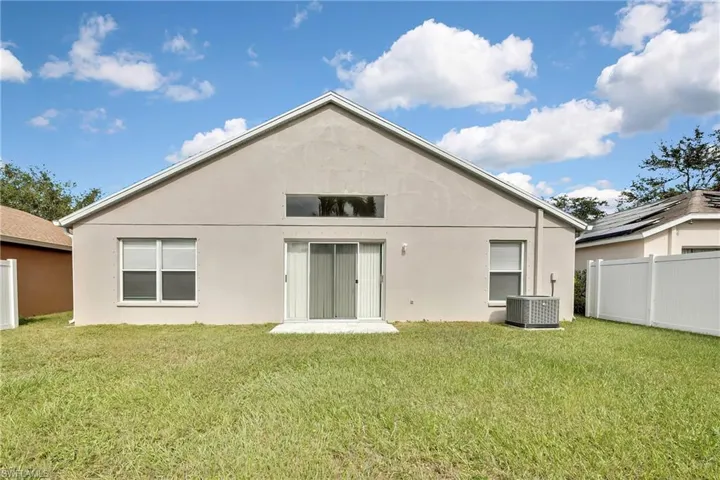 Back of house with central AC and a yard