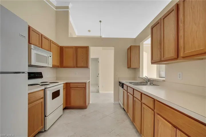 Kitchen featuring white appliances, sink, and light tile patterned floors