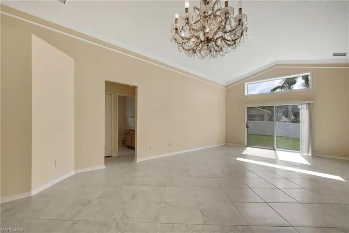 Tiled spare room with ornamental molding, a textured ceiling, a chandelier, and vaulted ceiling