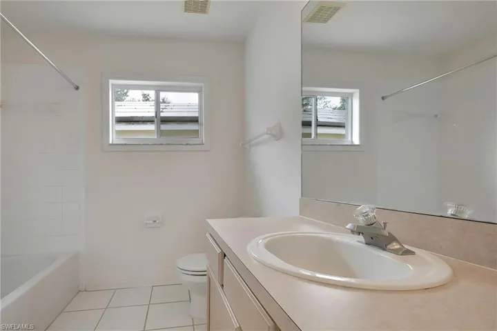 Full bathroom featuring vanity, a wealth of natural light, tile patterned floors, and toilet
