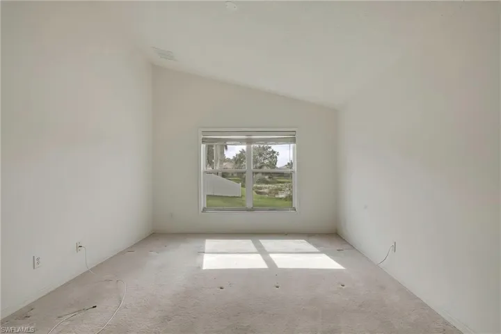 Carpeted empty room with lofted ceiling